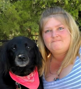 Woman posing with black dog wearing red bandana