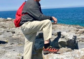 Man with red backpack on rocky coast