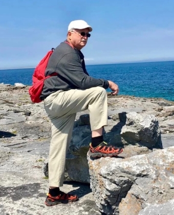 Man with red backpack on rocky coast