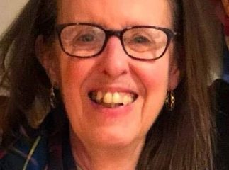 Smiling woman with glasses and plaid scarf