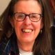 Smiling woman with glasses and plaid scarf