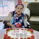 Elderly woman with birthday cake and party hat