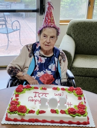 Elderly woman with birthday cake and party hat