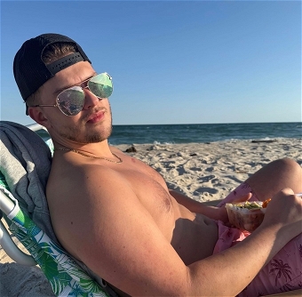 Man relaxing shirtless on beach with sandwich