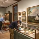 Visitors examining artwork and artifacts in museum gallery