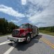Red fire engine on rural road under blue sky