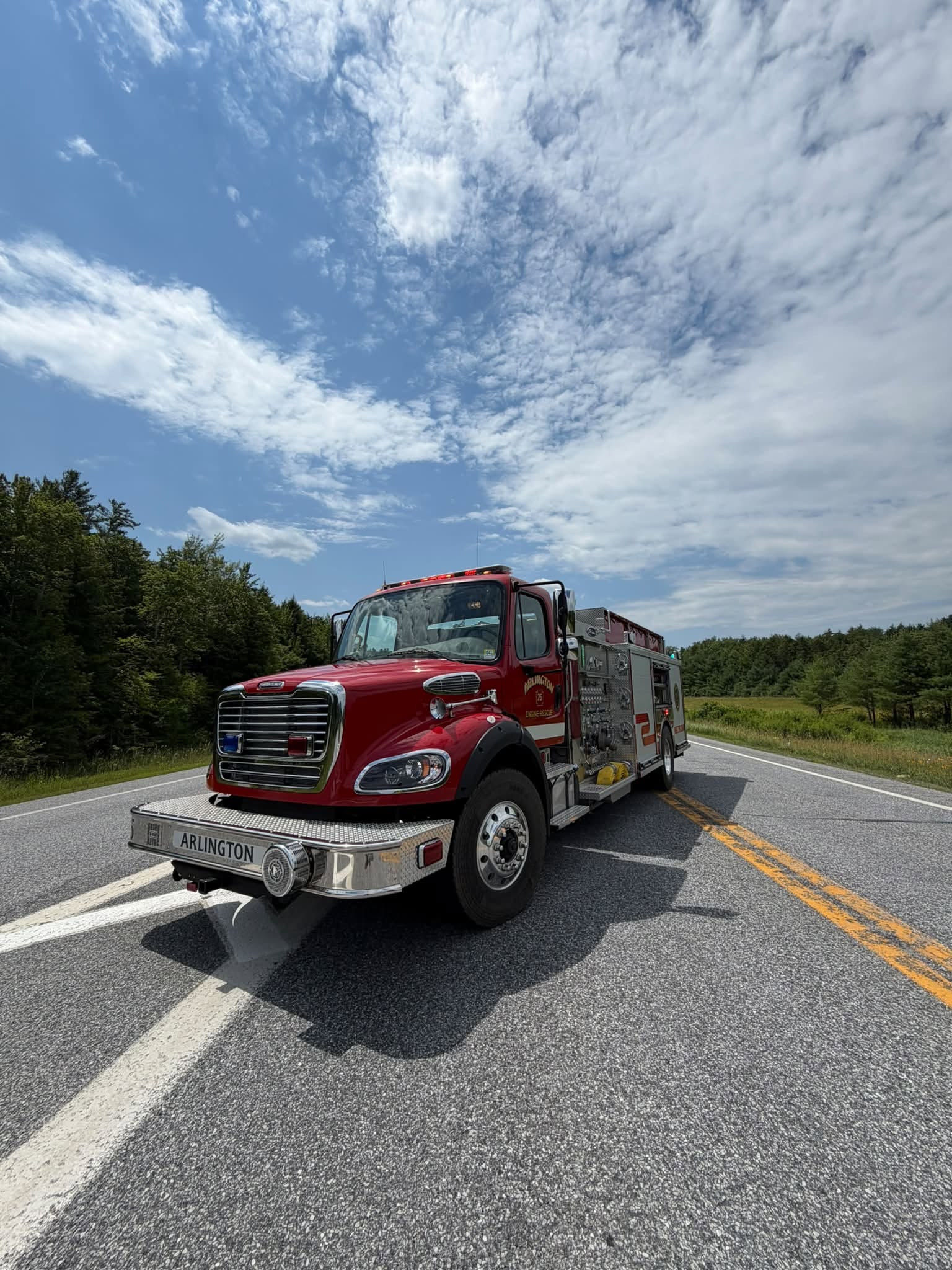 Red fire engine on rural road under blue sky
