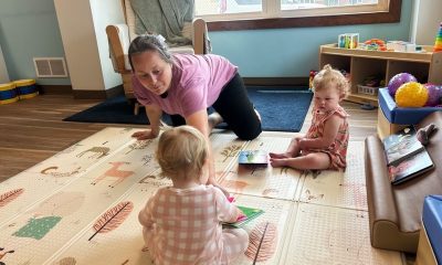 Woman playing with two toddlers on play mat