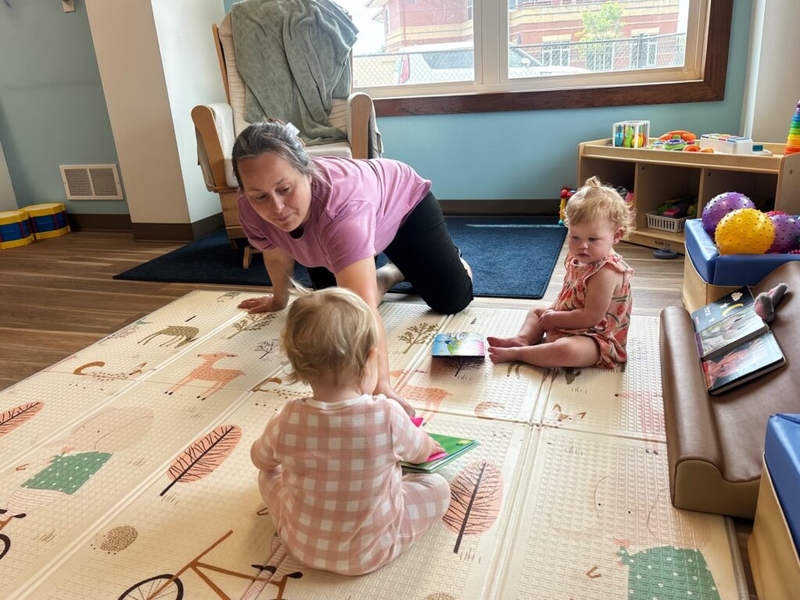 Woman playing with two toddlers on play mat