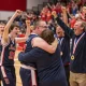 Basketball team celebrating championship victory with coach hug