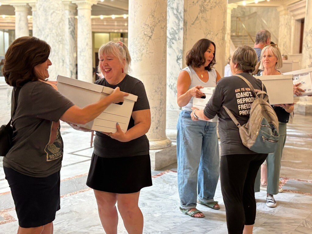 Women carrying document boxes inside marble government building