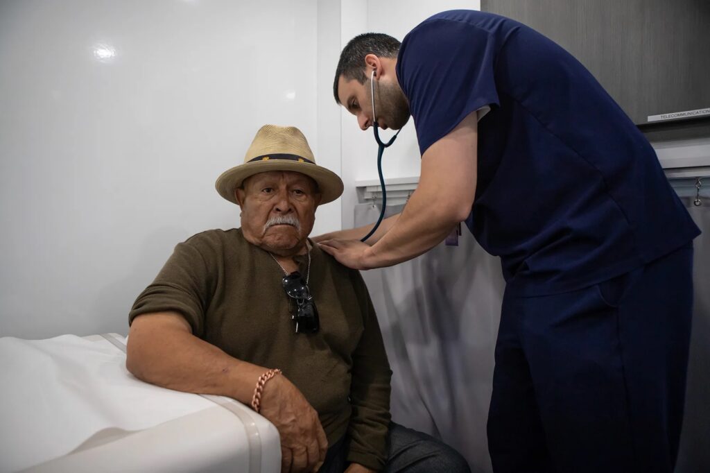 Doctor examining elderly man with stethoscope