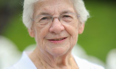 Elderly woman smiling outdoors with white corsage