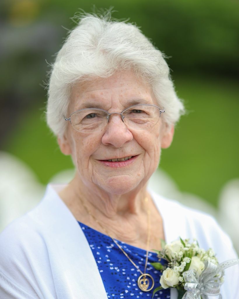 Elderly woman smiling outdoors with white corsage