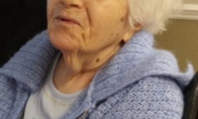 Elderly woman in blue sweater sitting indoors