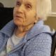 Elderly woman in blue sweater sitting indoors