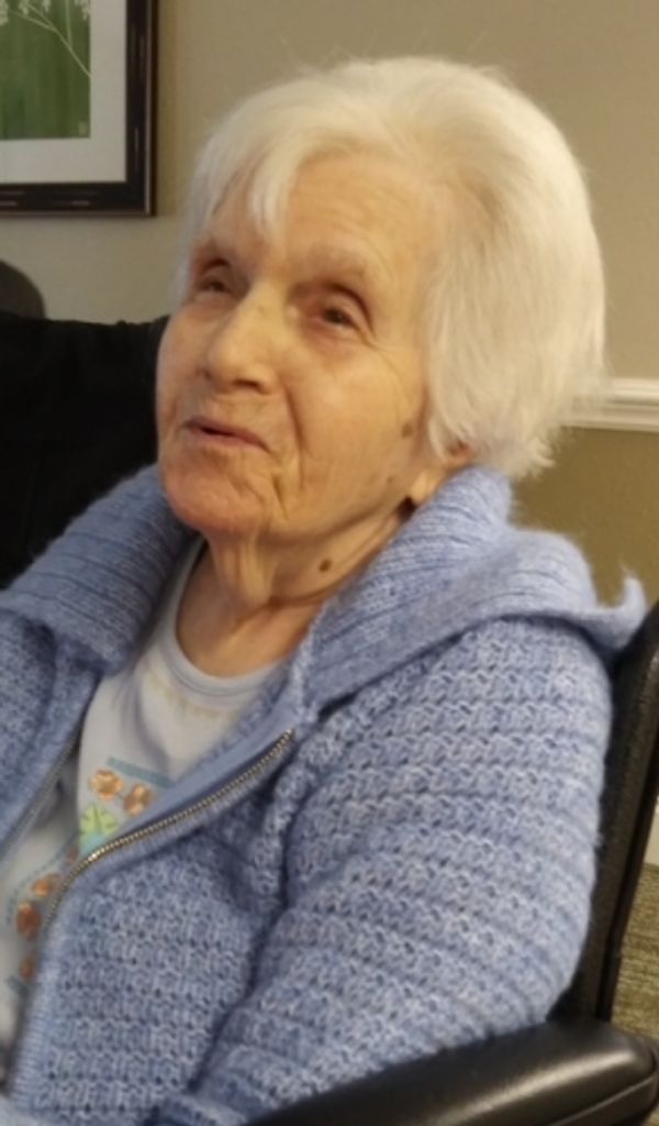 Elderly woman in blue sweater sitting indoors