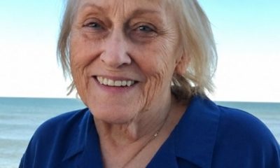 Smiling elderly woman at beach with ocean backdrop