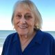 Smiling elderly woman at beach with ocean backdrop