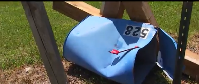 Damaged blue mailbox lying on the ground