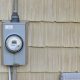 Electric meter mounted on beige house siding
