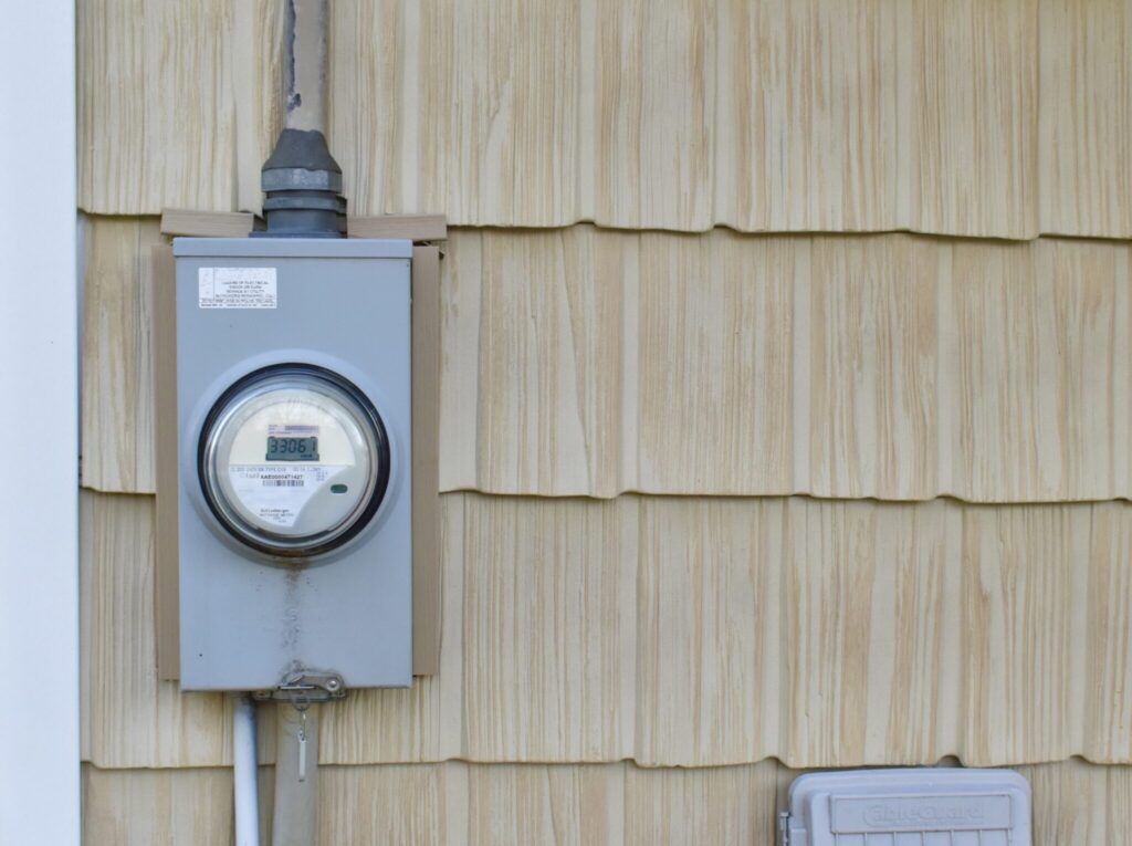 Electric meter mounted on beige house siding