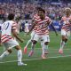 Soccer players celebrating goal in packed stadium