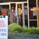 People entering polling place with Vote Here sign