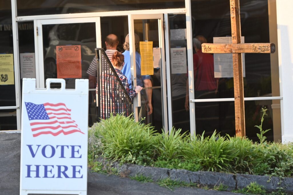 People entering polling place with Vote Here sign