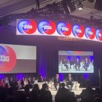 A panel discussion at a conference featuring speakers on stage, with an audience in the foregro — Phil Scott states rights
