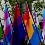 Colorful LGBTQ flags waving at a public event, symbolizing diversity and inclusion. — LGBTQ healthcare barriers