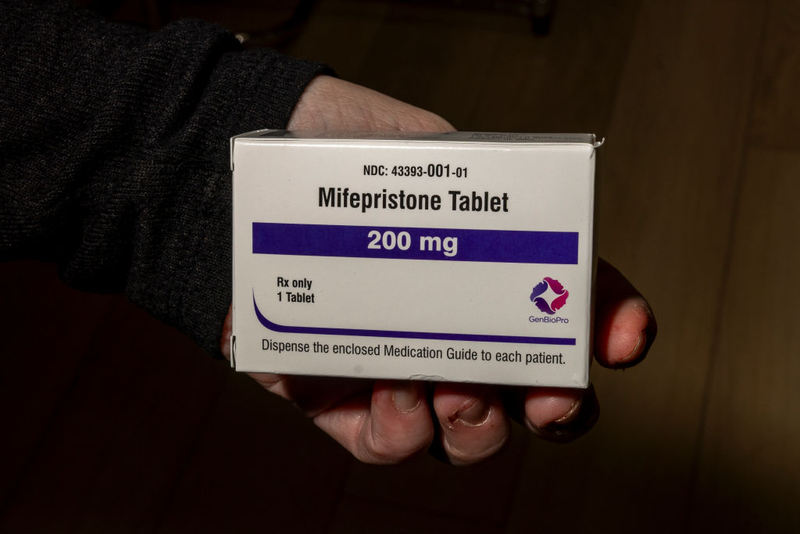 A hand holding a box of mifepristone tablets, labeled 200 mg, emphasizing the medication's i — mifepristone lawsuit paused