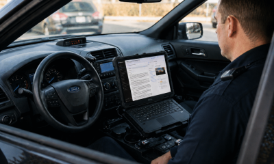 Police officer using laptop inside patrol car — AI in policing Pensacola