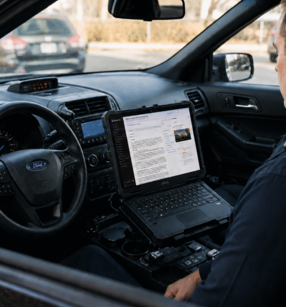 Police officer using laptop inside patrol car — AI in policing Pensacola