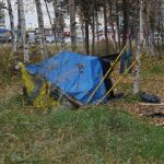 A makeshift tent in a wooded area, surrounded by autumn foliage, highlighting issues related to federal homelessness grants.