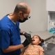 A dentist examining a young girl in a dental office, highlighting immigrant children missing healthcare.