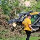 Two women discuss cleanup efforts near a tree debris pile and a construction vehicle after a storm, hi — FEMA disaster aid