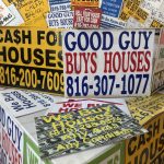 Colorful signs advertising cash offers for homes, featuring phone numbers and phrase — real estate wholesaling regulations