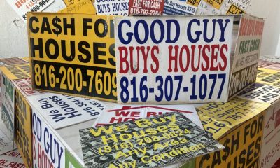 Colorful signs advertising cash offers for homes, featuring phone numbers and phrase — real estate wholesaling regulations