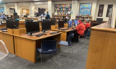 Library interior with computers, students using them, and a welcome sign on the wall, highlighting E-Rate program funding…