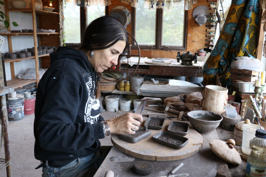 A woman working on pottery in a cozy studio filled with various tools and materials. — alpha-gal syndrome