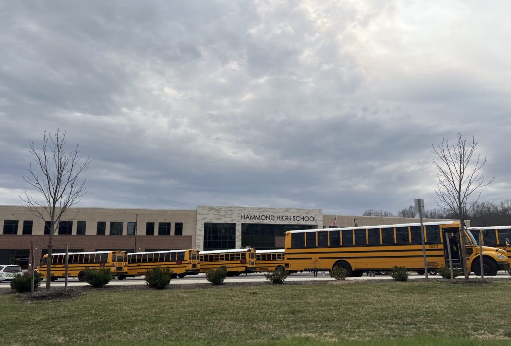 Hammond High School with several yellow school buses parked in front under a cloudy sky, — violent victimization at school
