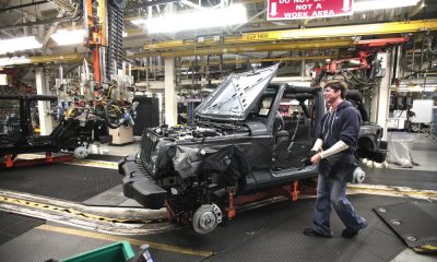 An auto worker in a factory is assembling a vehicle amidst machinery and equipment, highlighting — Trump Canada trade war