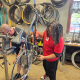 A young person in a red shirt adjusts a bicycle in a workshop with bike tires in th — upstate new york bike infrastructure