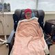 A woman in a hospital chair, wrapped in a blanket, smiling while receiving treatment for cancer. — cancer vaccine hesitancy