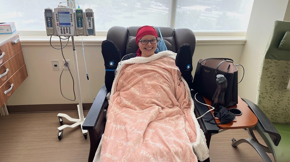A woman in a hospital chair, wrapped in a blanket, smiling while receiving treatment for cancer. — cancer vaccine hesitancy