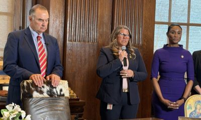 Three individuals stand in a formal setting discussing no-fault divorce laws, with one speaking into a microphone.