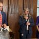 Three individuals stand in a formal setting discussing no-fault divorce laws, with one speaking into a microphone.