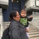A woman holding a young child outside a building, both smiling, with the number 66 — trump green card restrictions lawsuit