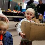 Two children at a food distribution event, one holding a box of snacks and the other with a — US poverty rate census data